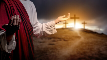 Jesus Christ raising his hand and praying with the Christian cross on the hill with dark dramatic...