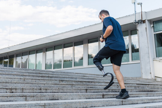 Man with a disability, wearing prosthetic equipment, a running blade, running up the city stairs. Leg prosthesis, sport and recreation concept. - Powered by Adobe