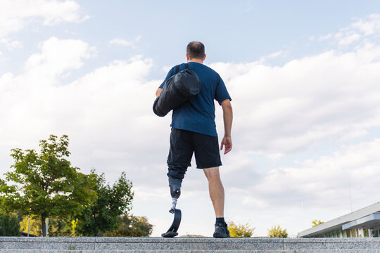 Man with disability performs workout routines while wearing a prosthetic leg in an urban outdoor setting during daytime.