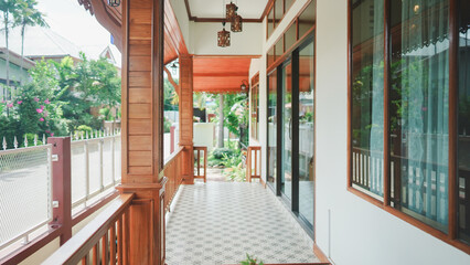 A traditional Thai-style wooden porch with tiled floor and garden view, showing warm tropical residential architecture.
