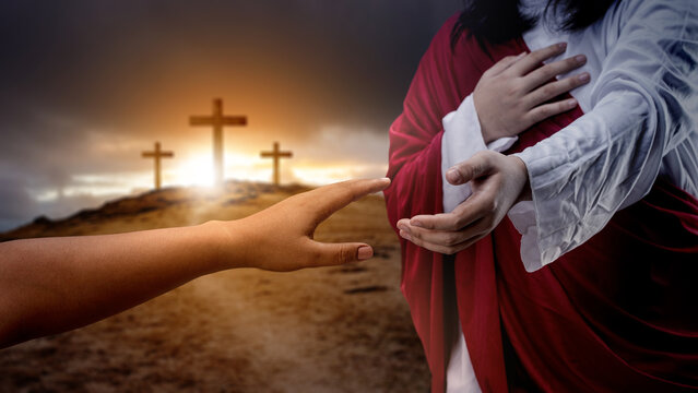 Jesus Christ hand offering a helping hand with a Christian cross on dark dramatic sky background. Concept of Christianity, religious, faith, Jesus, or belief