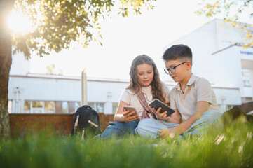 Students using smartphones sitting on grass outdoors