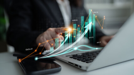 A business professional conducts financial analysis using a laptop, enhanced by digital graph visuals that represent economic trends and business growth in a modern office environment. Scalp