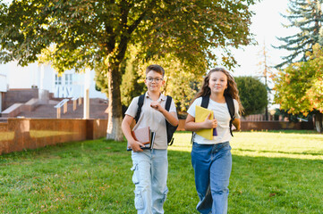 Young students happily running to school through park