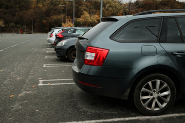 Row of parked vehicles in an outdoor parking lot on a cloudy day. The concept conveys daily routine, transport, and urban life