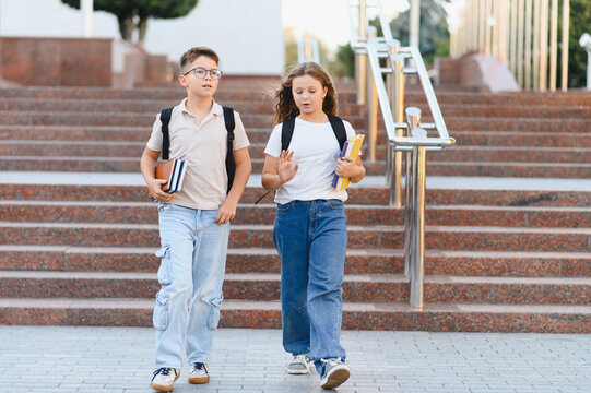 School children walking downstairs carrying backpacks and books