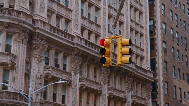 Street light with red on hanging over the road. Stunning historical architectural design of the high-rise building at backdrop. New York, United States.