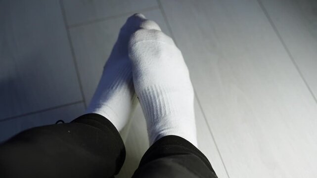 White high socks on a man's feet.
A man stamps his foot on a white wooden floor.
Warm socks on a guy's feet in a cold room.
Socks, clothes, warm, leg, put on, white, underwear