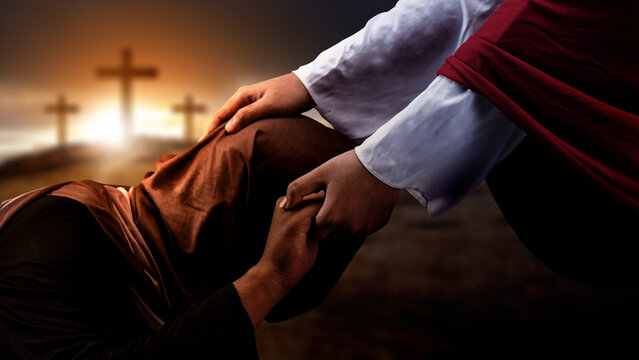 Jesus Christ hand offering a helping hand with a Christian cross on dark dramatic sky background. Concept of Christianity, religious, faith, Jesus, or belief