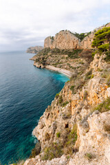Seascape. Rocky cliffs with calm turquoise waters. Coastal landscape. Secluded bay with a beach surrounded by a vibrant sea. Nature concept.