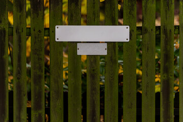 Zielony drewniany płot z pustą tabliczką adresową © Kacper