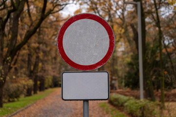 Znak zakazu wjazdu na drodze w parku jesienią – symbol ograniczenia i przepisów ruchu drogowego