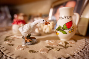Ceramic goose figurine on embroidered tablecloth
