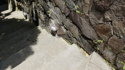 Outdoor granite stairs ascending next to stone walls. The steps are dusty with dried leaves, showing architecture and natural texture