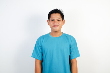 A cheerful young Asian man in a blue shirt stands against a white backdrop, smiling warmly. Conveys friendliness, casual energy, and approachability for lifestyle and wellness contexts.