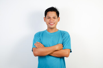 Portrait of a smiling young Asian man in a blue shirt standing confidently with crossed arms. Isolated on white background.