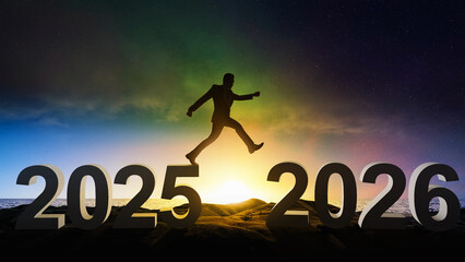 Silhouette of a businessman jumping over 2025 and 2026 with a sunny sky background. Happy New Year concept or Celebration