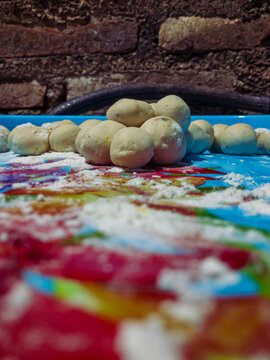 Cilok dough balls are being shaped on a colorful surface with flour scattered around, showing a simple homemade preparation of Indonesian street snack.