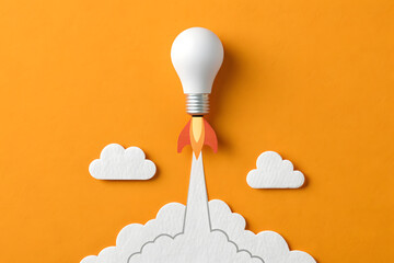 Paper-craft light bulb rocket on orange