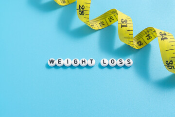 Yellow tape measure with text Weight Loss on light blue background