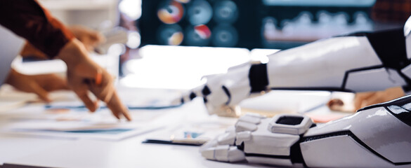 A futuristic business meeting scene featuring a robot arm collaborating with humans over data analysis and strategy planning in a modern office setting.Noogenesis