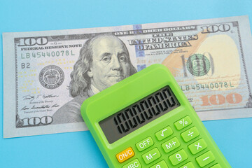 Business concept with dollar banknote and calculator on light blue background
