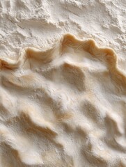 Close-up of flour and dough on a wooden surface, ideal for baking and cooking. The image captures the texture and preparation process in a kitchen setting.
