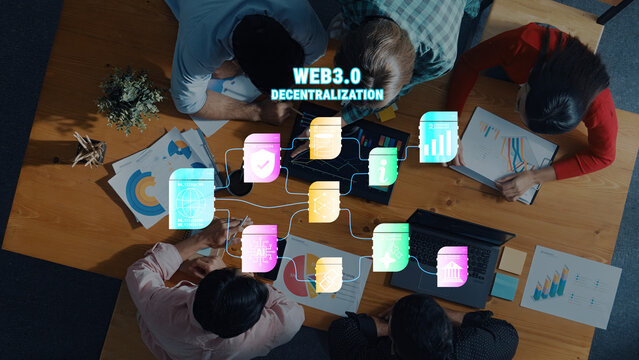 A diverse group of professionals collaborates around a wooden table, discussing web3.0 and decentralization concepts with engaging digital infographics and visual data. Trope
