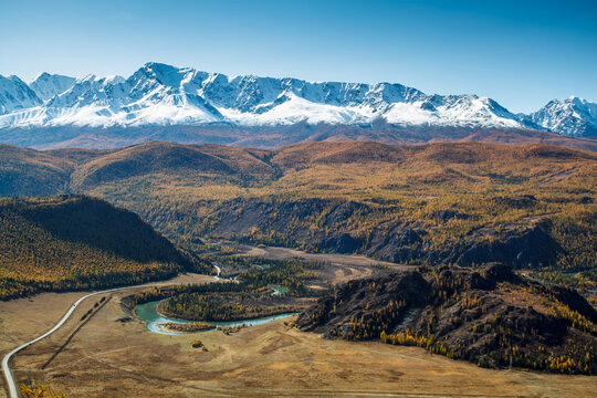 Breathtaking view of Altai region in autumn, featuring a winding river surrounded by vibrant foliage. Experience calmness and natural beauty in this tranquil landscape. Russia.