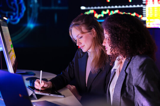 Colleagues discuss stock market trends in a modern office setting during evening hours
