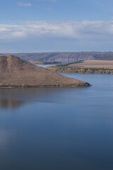 Scenic landscape of Bakota Bay in Khmelnytskyi region, Ukraine. Calm river, brown hills, and fields create a peaceful view of the Dniester Canyon area in autumn light.