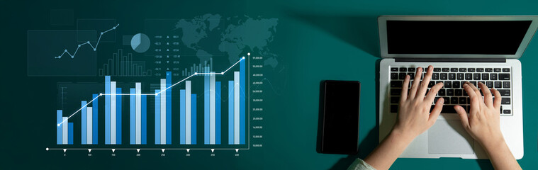 A close-up view of hands working on a laptop in a modern office setting, illustrating business...