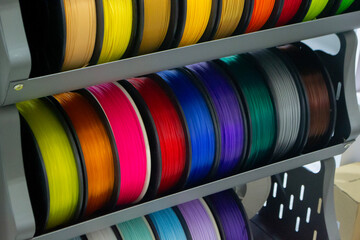 Many spools with multi-colored plastic for 3D printing. Spools with pink, red, burgundy, purple blue plastic wire for 3D printer. Components for 3D printing. Accessories for 3D printer. FDM technology