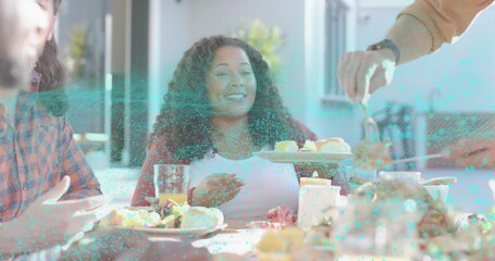 Smiling woman receiving pastry from serving tray while holding glass of juice at dining table