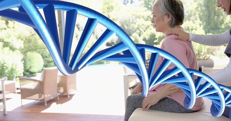 Sitting Asian woman wearing pink top receiving aide support on sunny patio, DNA helix, copy space