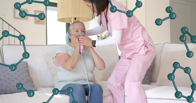 Helping nurse in pink scrubs stethoscope leaning toward patient on sofa at home, adjusting mask - Powered by Adobe