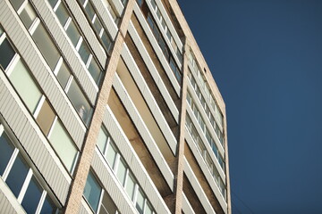 Soviet style apartment block with repetitive windows and balconies, photographed from low angle.