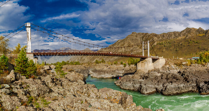 Stunning mountain bridge Oraktoy over turquoise river Katun amidst rugged landscape Altay Russia.