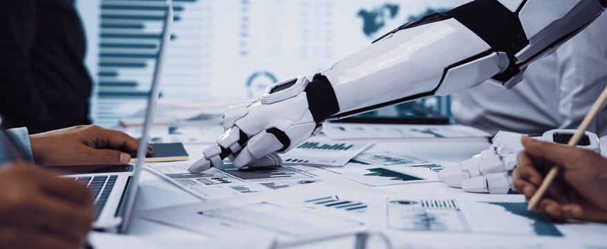 A futuristic robotic hand interacts with human colleagues in a sleek workspace, showcasing collaboration through data presentation and analysis with charts and graphs.Noogenesis