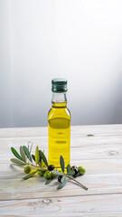 Small Glass Bottle of Olive Oil with Branch of Olives on Wooden Surface green