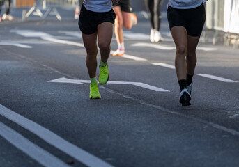 runners in a marathon showing close up on athletic legs and running shoes on city street