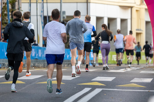 diverse runners participating in a marathon race running along an urban street in Ljubljana