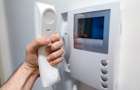 Man Hand Holding White Home Intercom Receiver.
