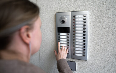 Woman rings the intercom from the street.