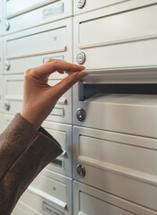 Woman checking mailbox in apartment building.