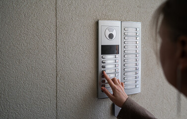 Woman rings the intercom from the street.