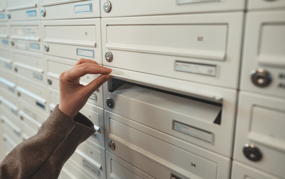 Woman checking mailbox in apartment building.