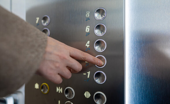 Woman pressing button inside elevator.