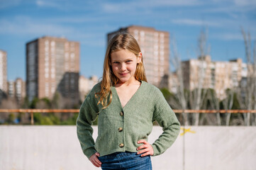 Blonde girl standing with hands on hips outside in an urban setting