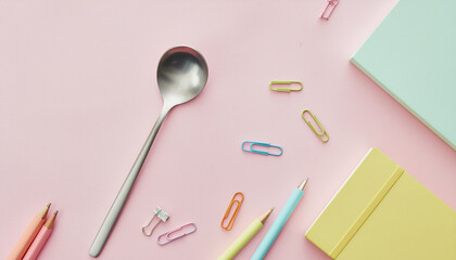 Spoon and stationery on pastel background showing hunger for education project inspiration and creativity